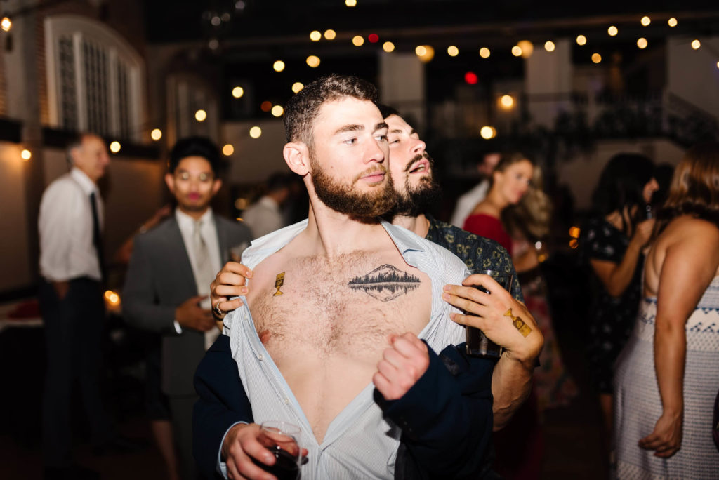 wild wedding reception dance party with guy taking his shirt off