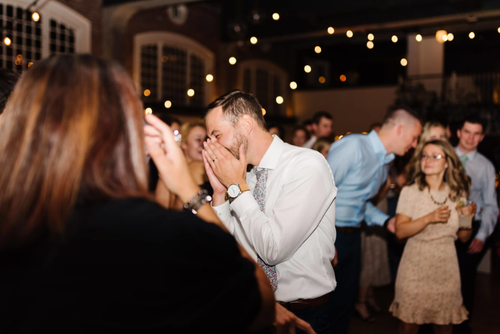 guy covering his face laughing on the wedding reception dance floor