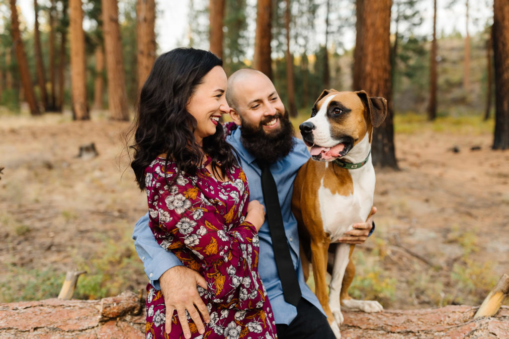 Couple and their boxer dog sitting on a log