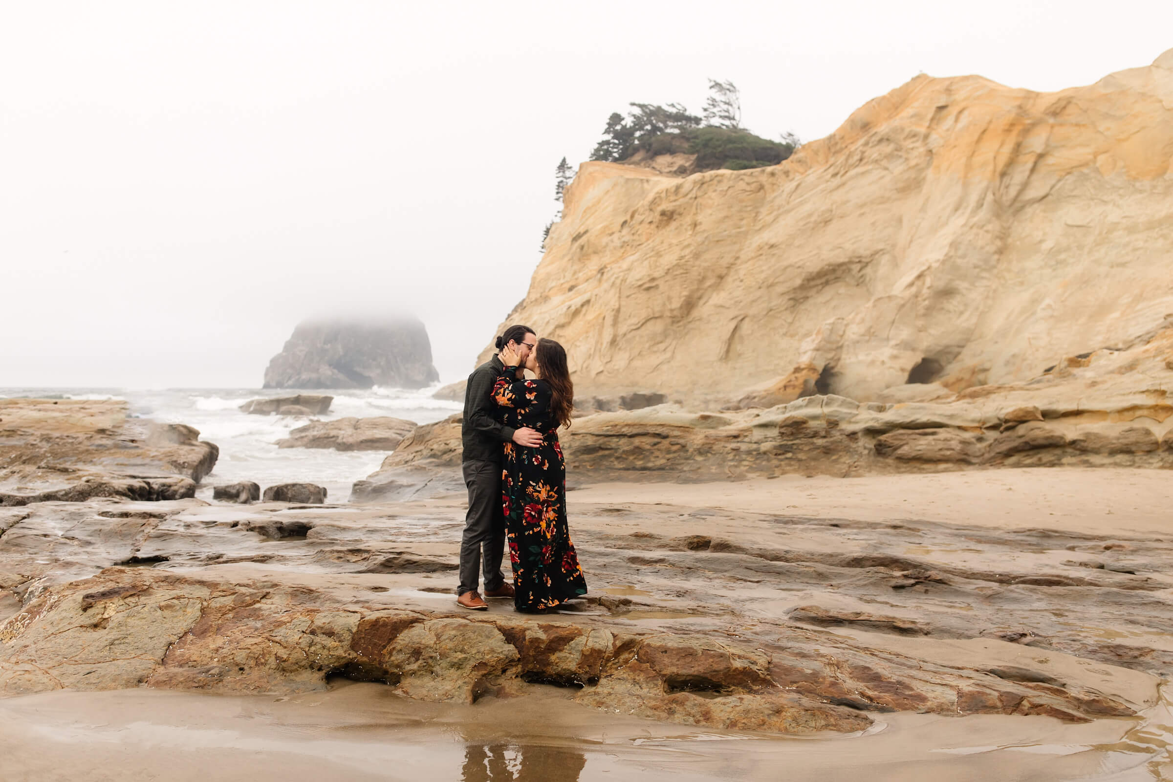 man and woman standing on rock kissing at Oregon coast