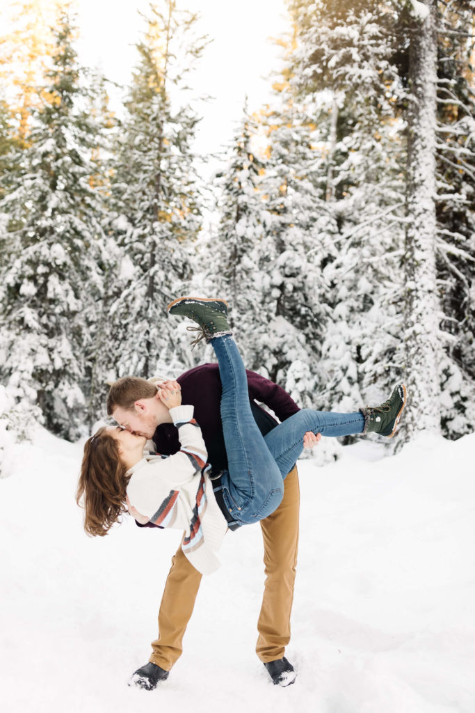 girl holding girl and dipping her for a kiss in the snow