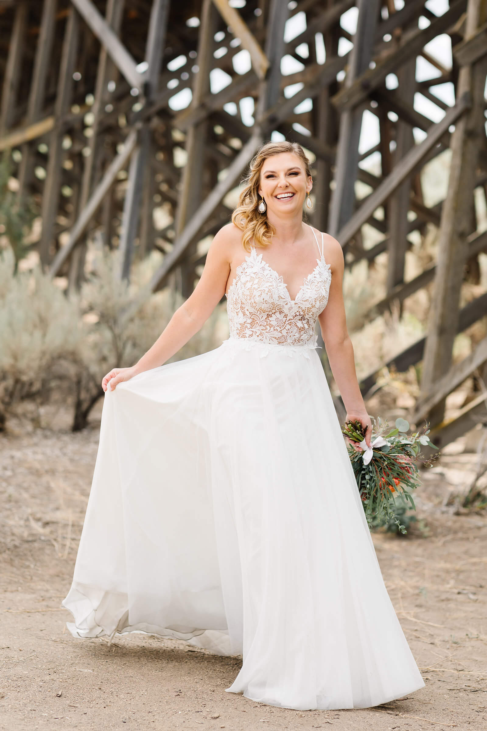 bride twirling in wedding dress next to bridge at brasada ranch