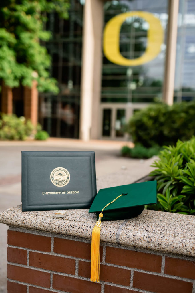 university of Oregon graduation diploma and graduation cap sitting on brick ledge