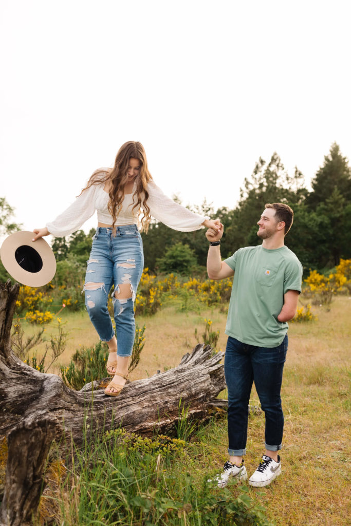 girl walking on log holding hand of male photographed by bend wedding photographer
