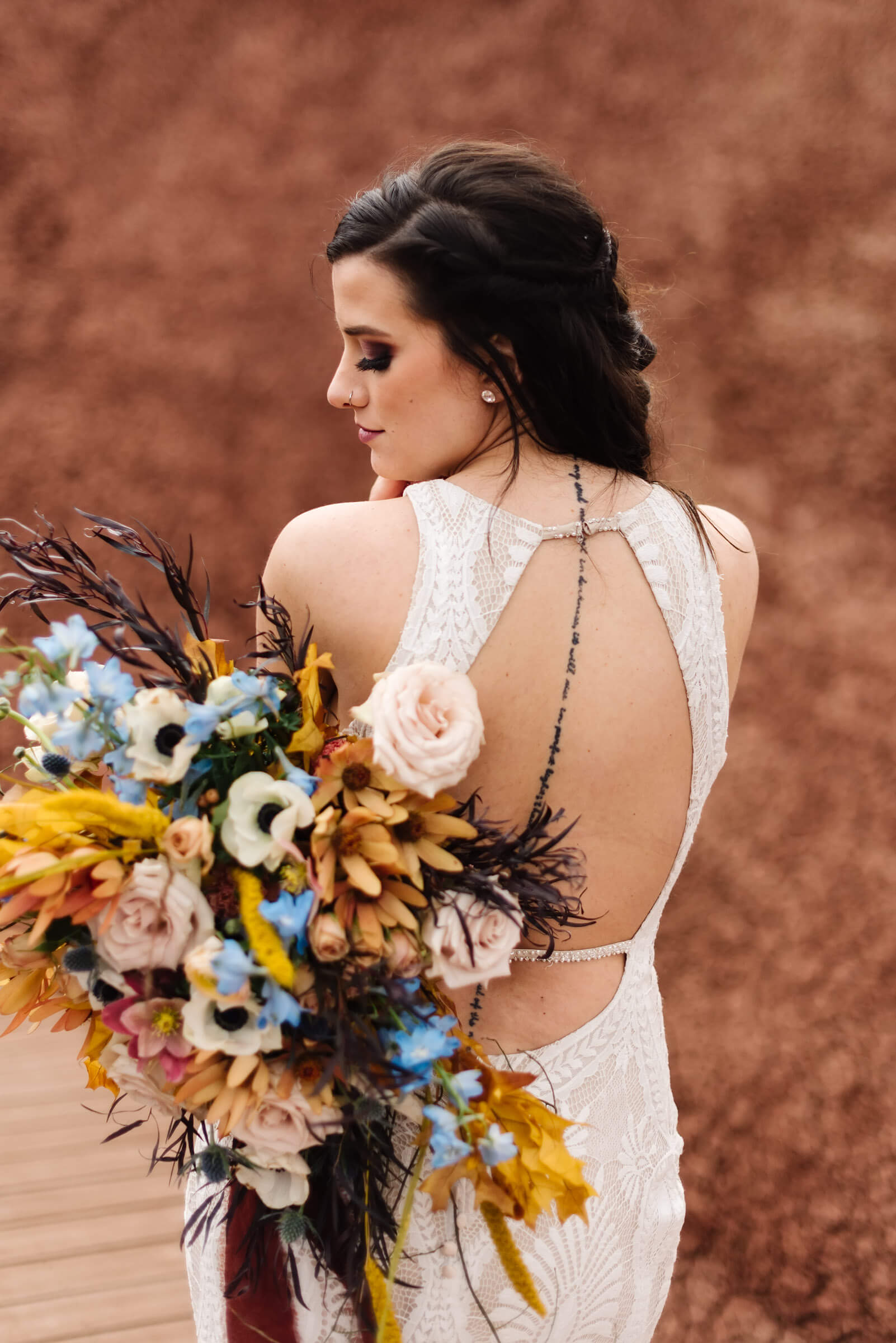 bride looking over shoulder and holding colorful bouquet at the painted hills