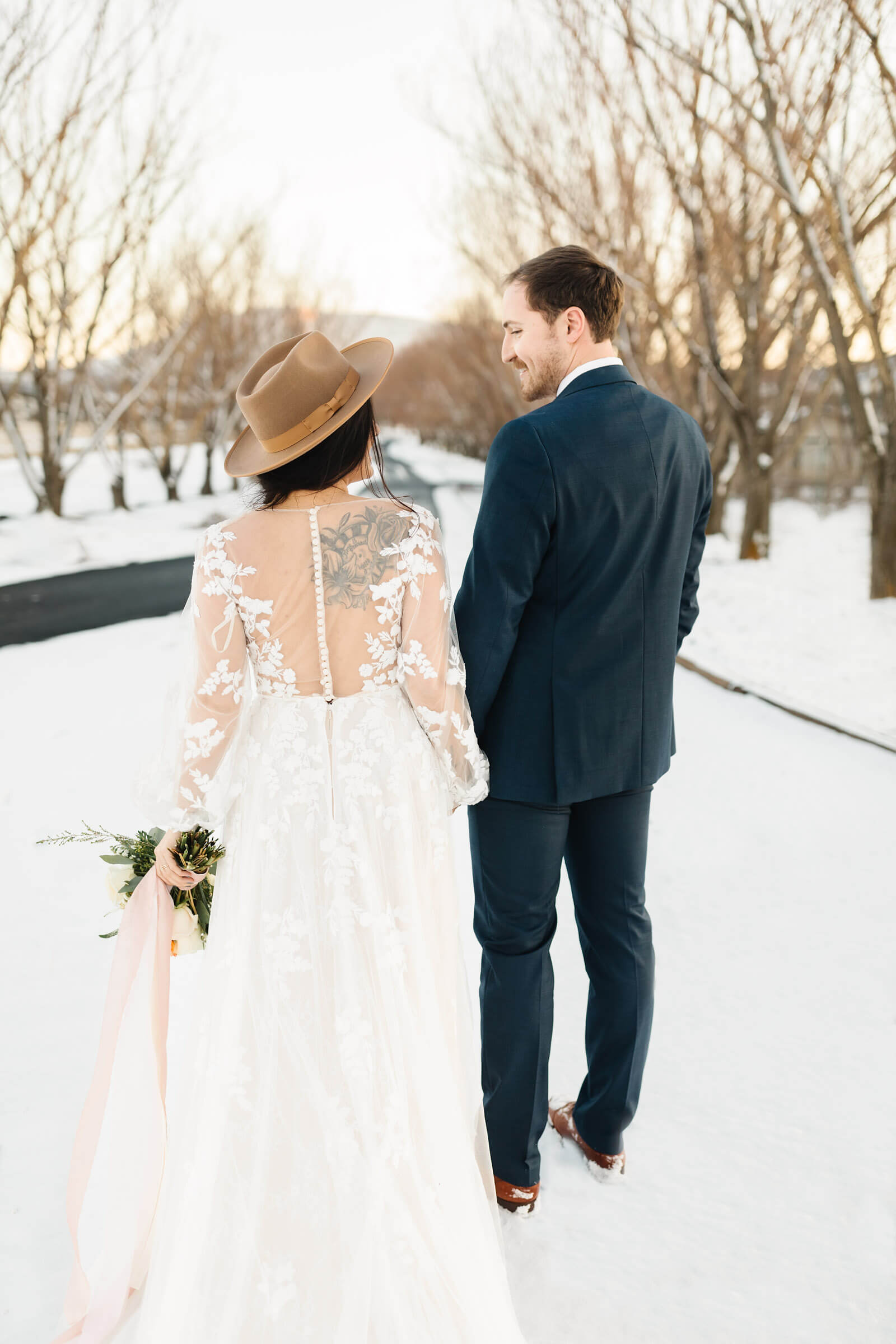 bride and groom holding hands walking down snowy path