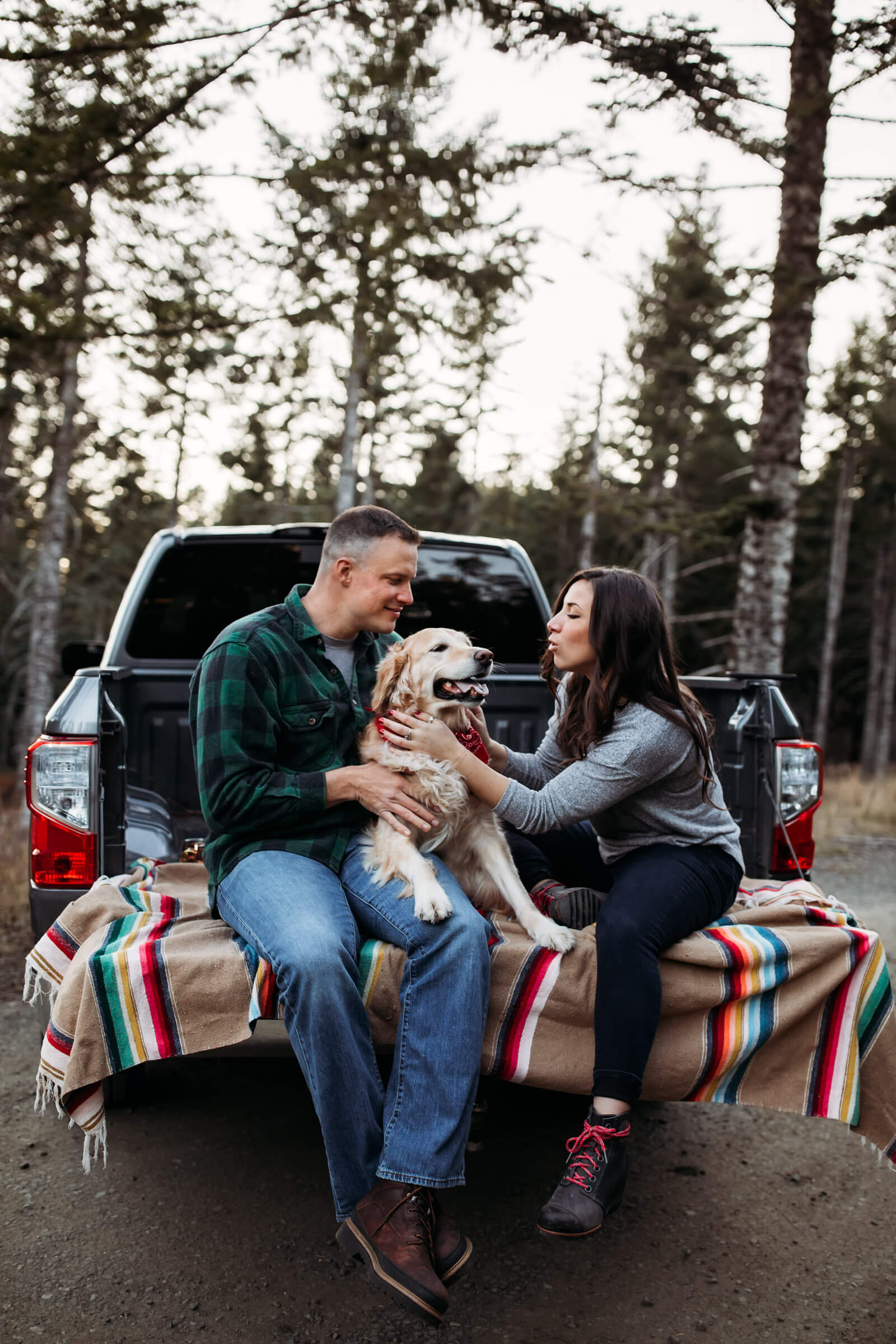 couple sitting on their truck bed petting their dog