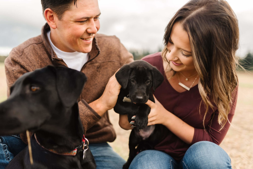 guy and girl holding black puppy