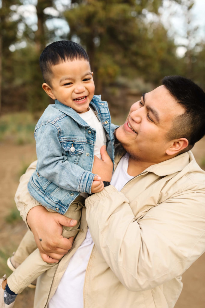 little boy in blue denim jacket being tickled by dad