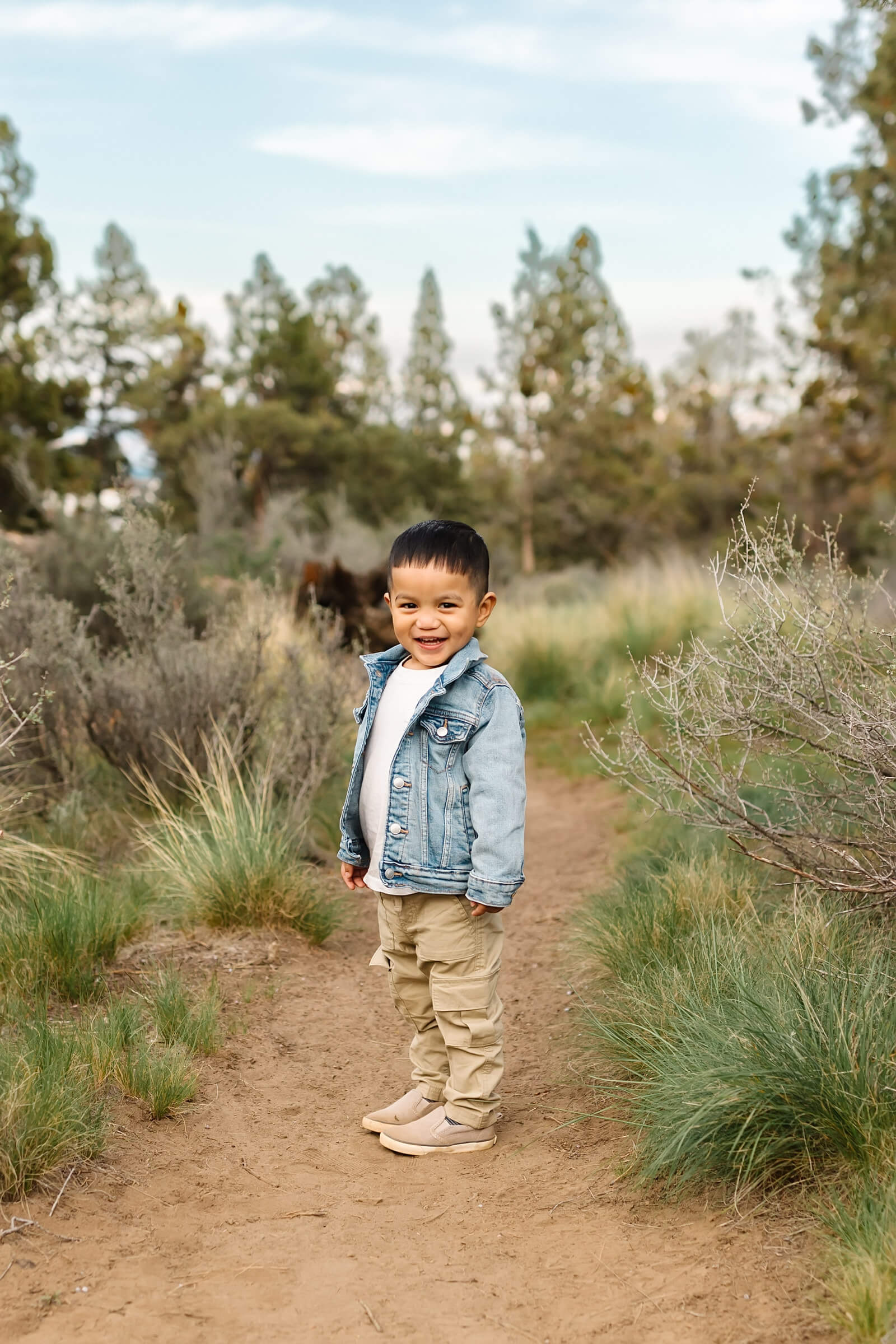 little boy with black hair wearing blue denim jacket smiling