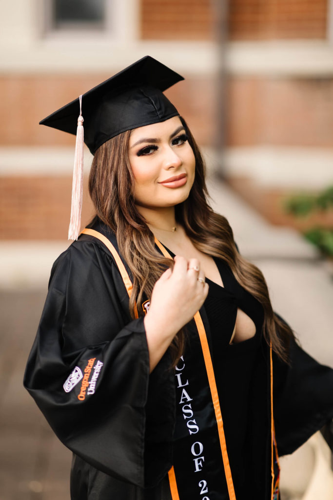 girl in Oregon State Graduation cap and gown in front of Weatherford Hall