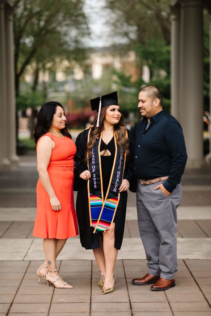 girl in Oregon State Graduation cap and gown with parents in front of Weatherford Hall
