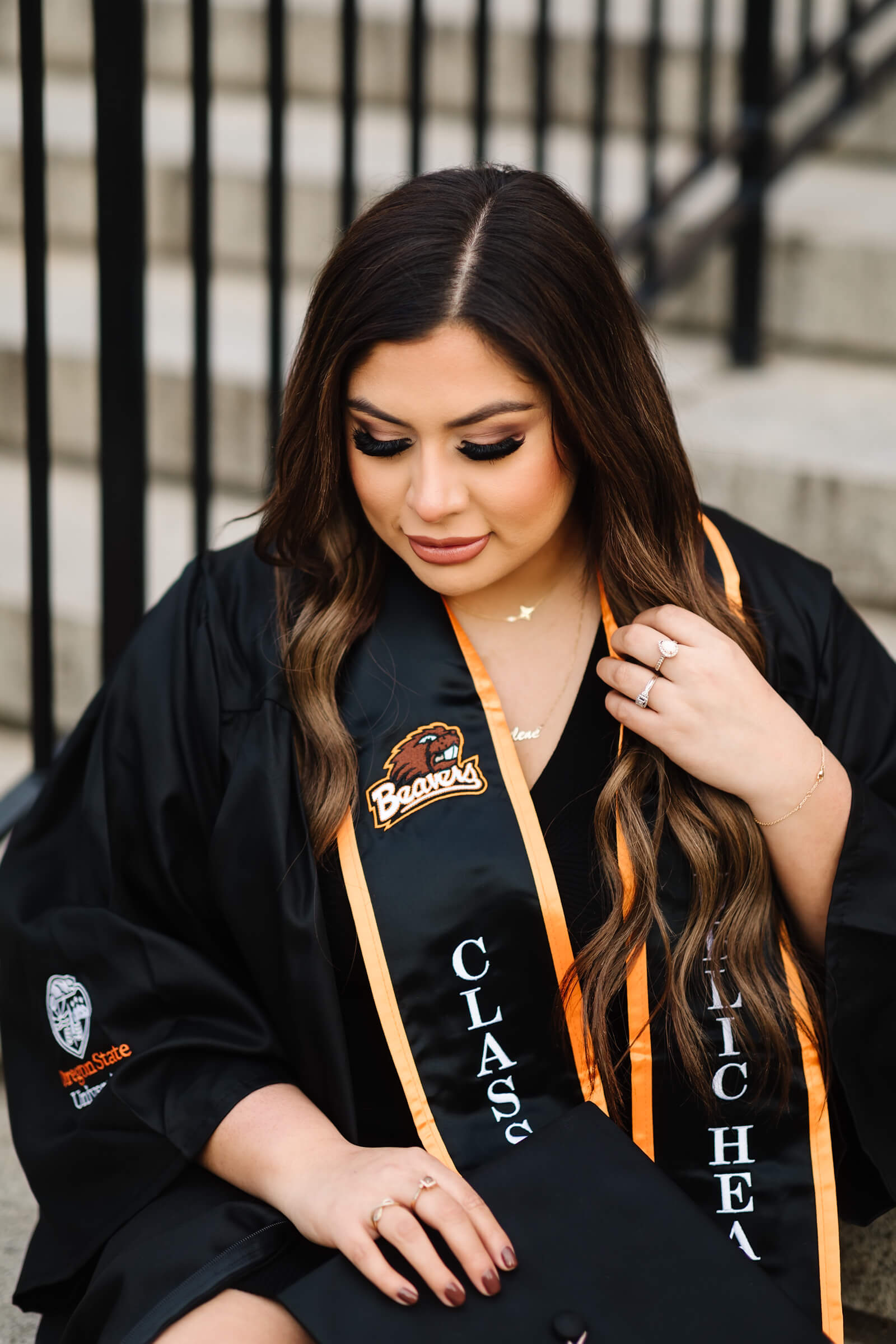 close up portrait of girl in Oregon State Graduation cap and gown sitting in front of MU Building at Oregon State