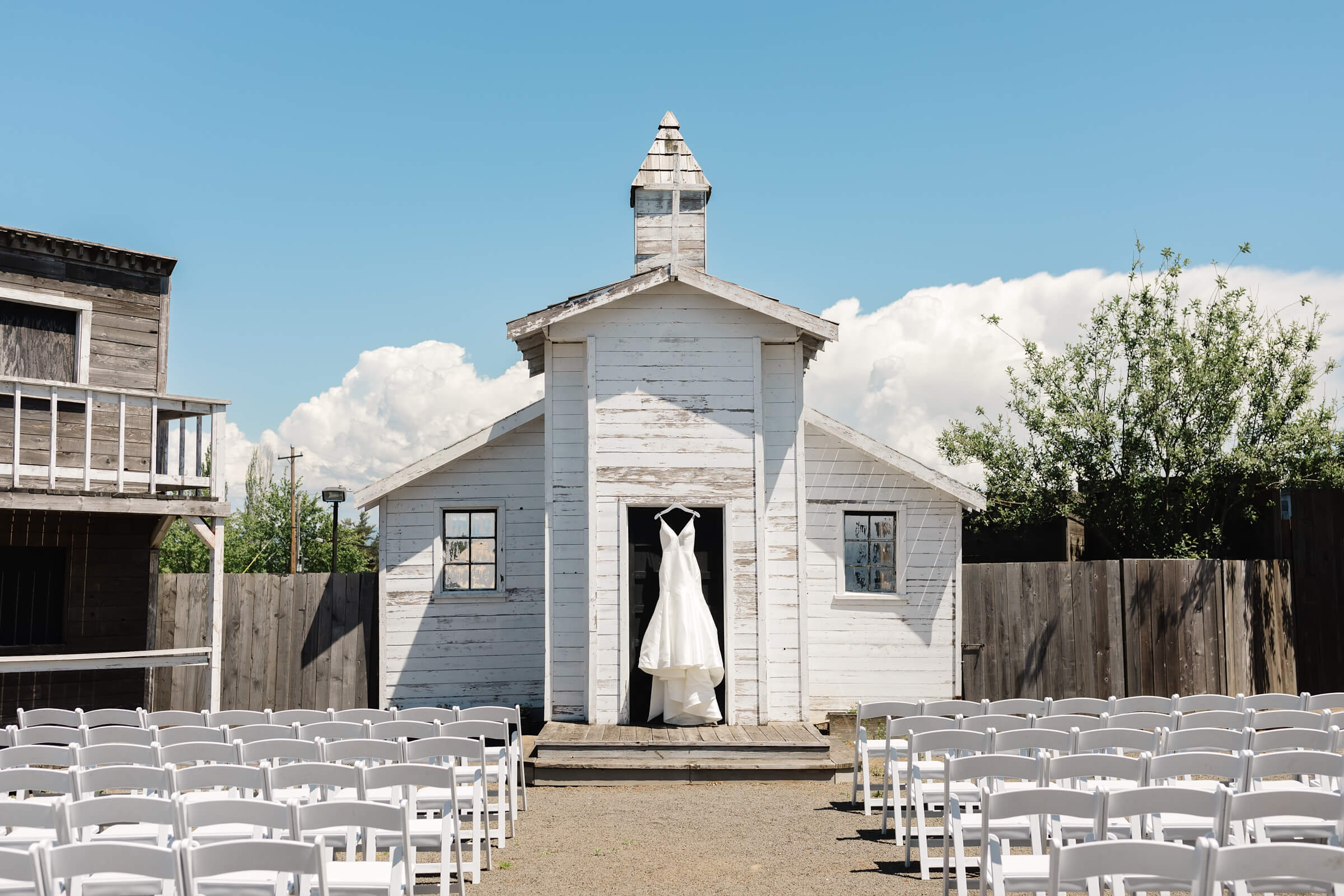 white wedding dress hanging from white wedding chapel