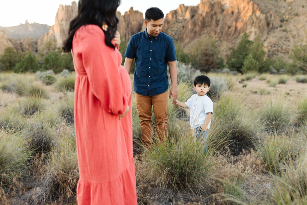 pregnant woman in coral dress during maternity photoshoot at smith rock