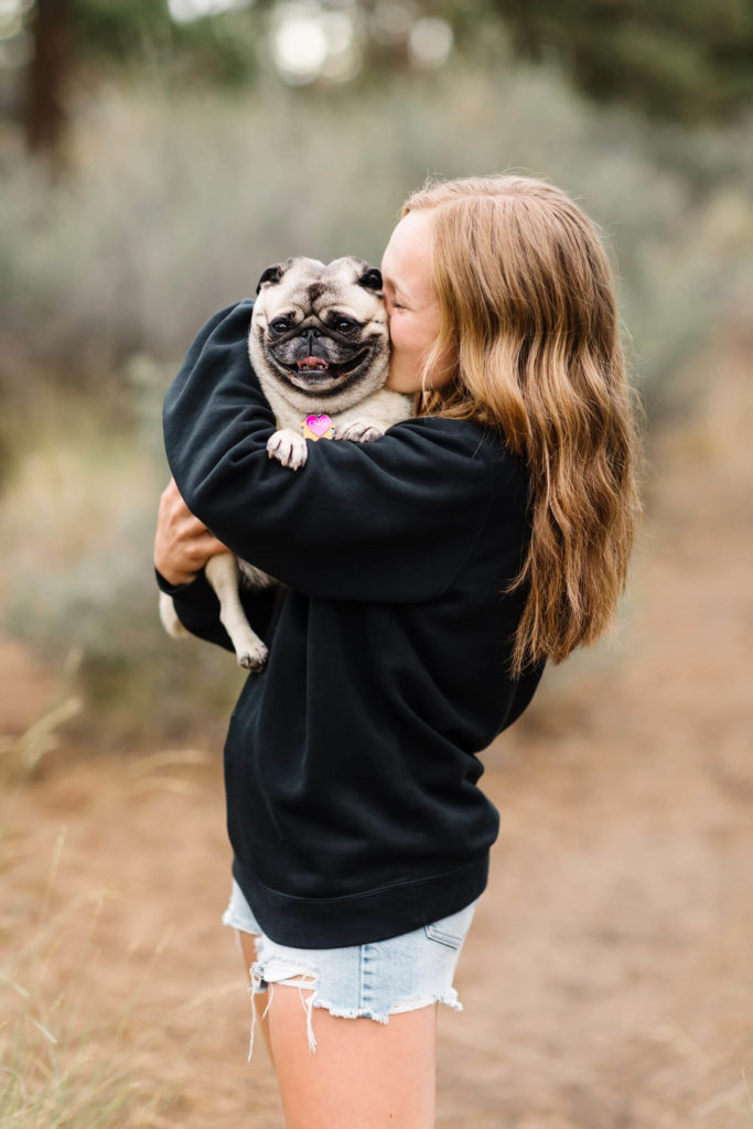 blonde girl in black sweatshirt kissing pug at Sawyer Park Bend oregon