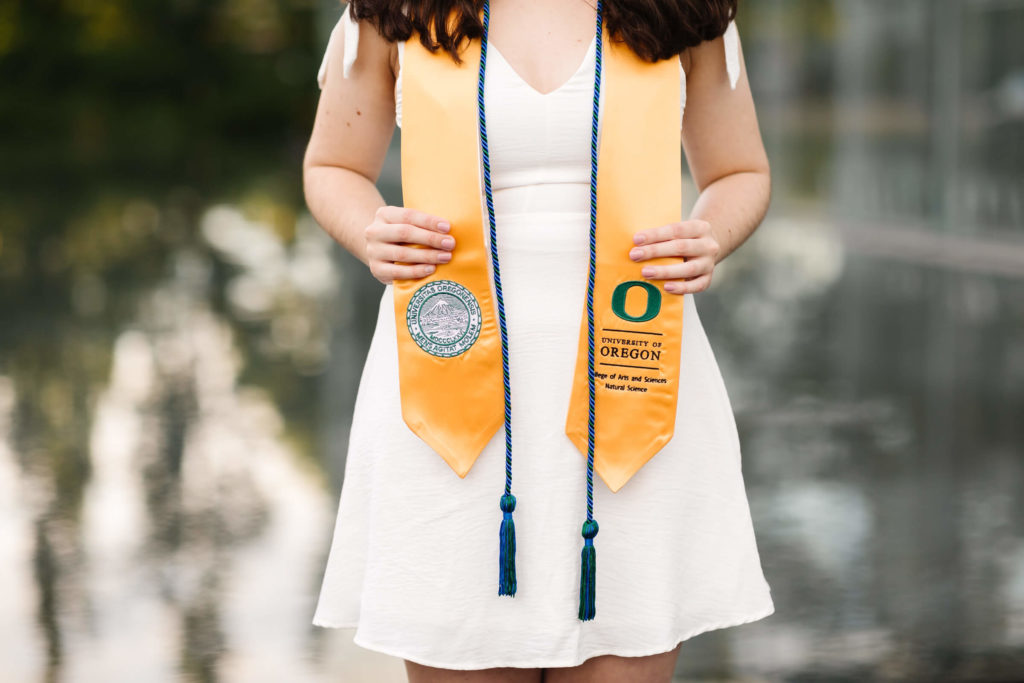 girl in white dress wearing yellow university of Oregon graduation sash