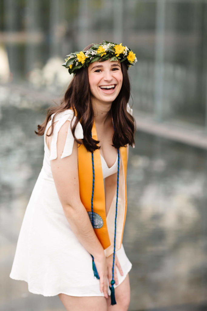 girl at white dress laughing wearing green and yellow flowered traditional haku 