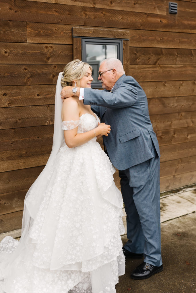 a grandpa putting a special necklace on the blonde bride in a large wedding ball gown