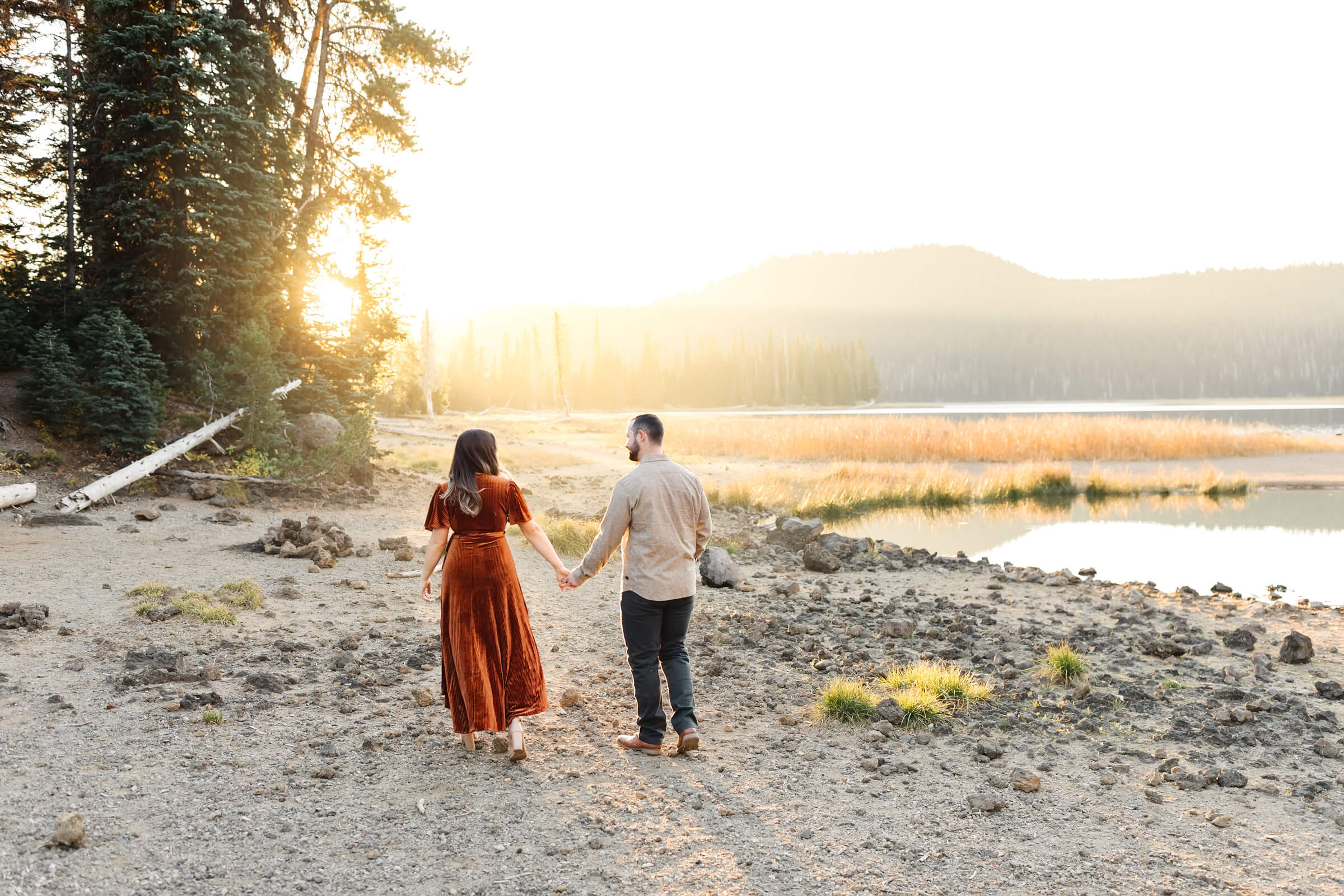 girl in orange velvet dress holding hands with male walking by sparks lake