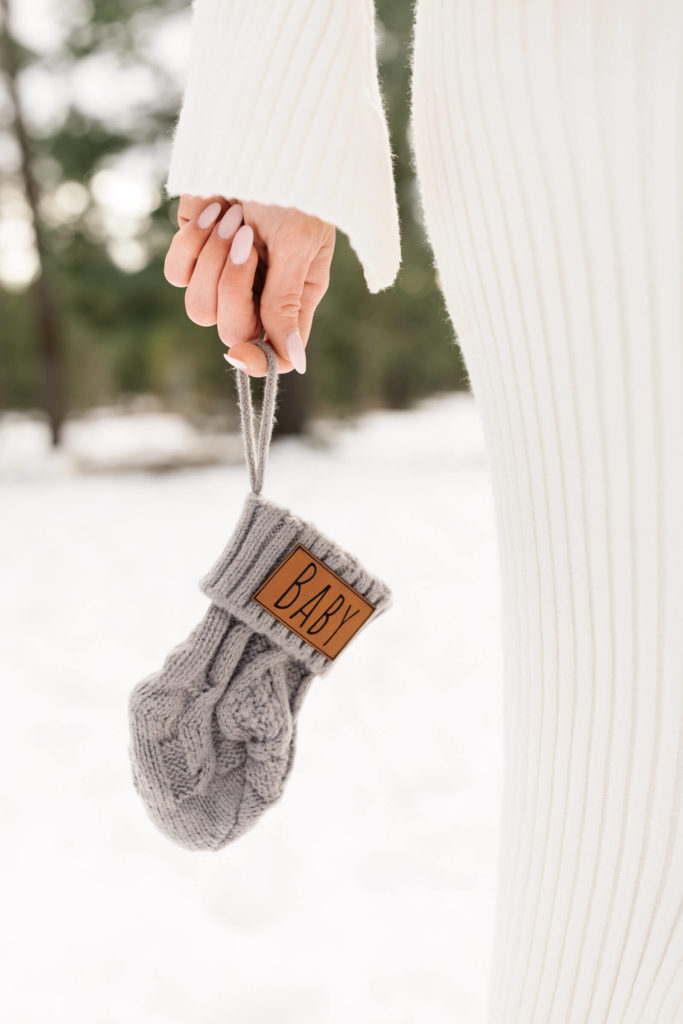 woman holding tiny stocking that says baby during pregnancy announcement shoot