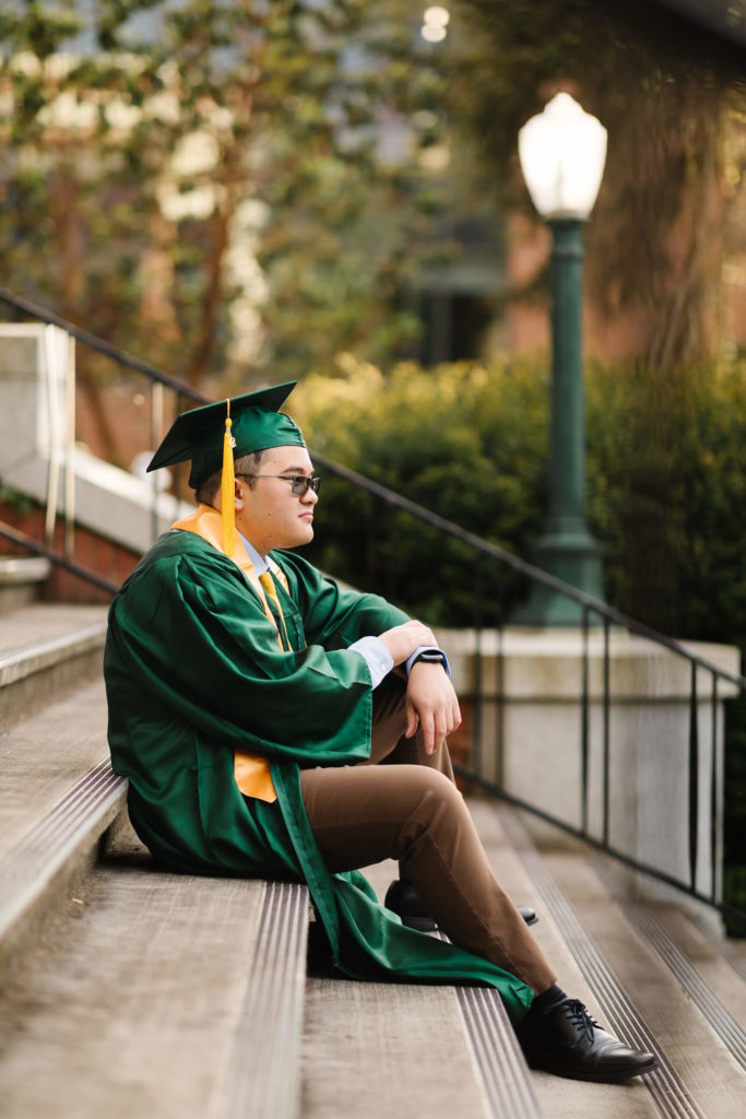 University of Oregon male student sitting on steps of Johnson Hall during Hayward field graduation photos