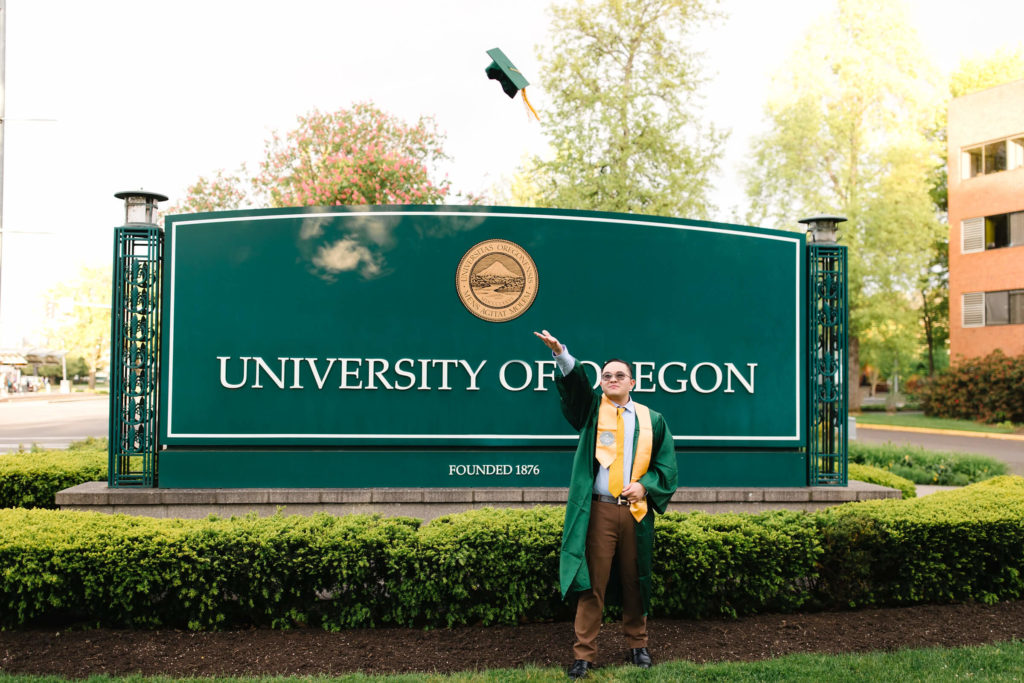 Male University of Oregon student tossing graduation cap while at hayward field graduation photos