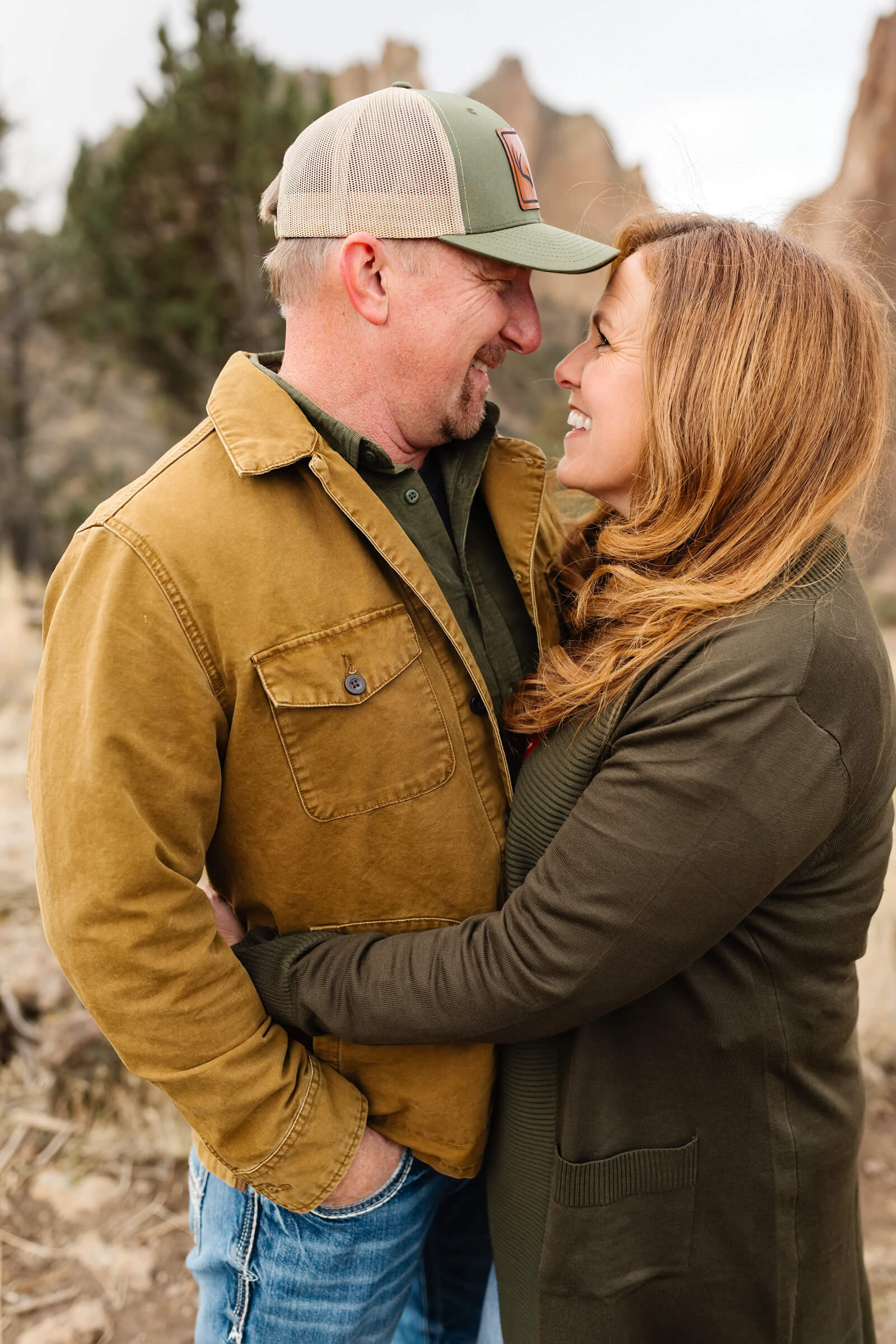 a mother and father dressed in neutral tones hugging and looking at each other during smith rock family photoshoot
