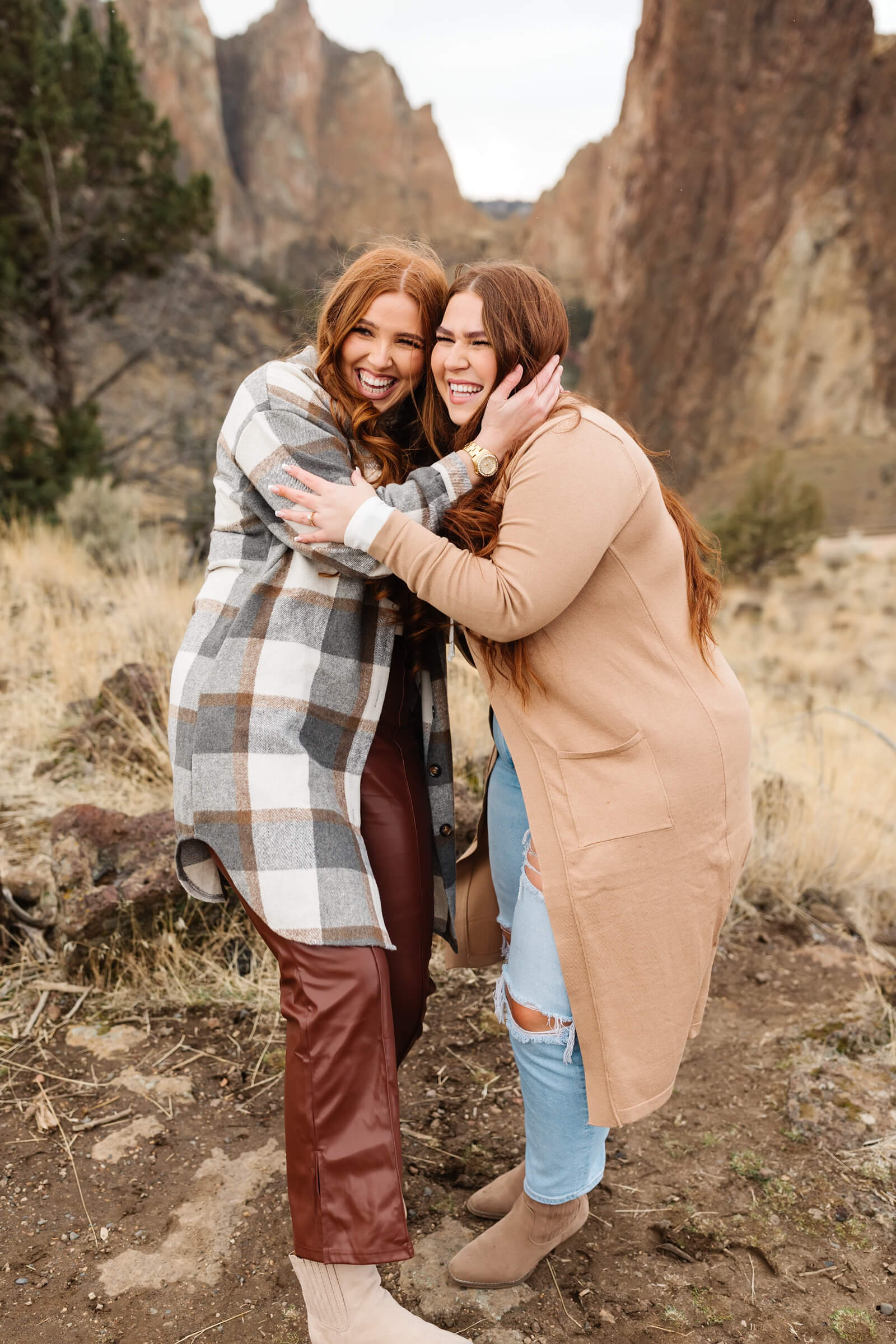 sisters with red hair and plaid gray shacket embracing at smith rock family photoshoot