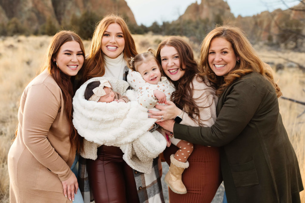 a group of women with red hair holding two babies and hugging each other at Smith Rock family photoshoot