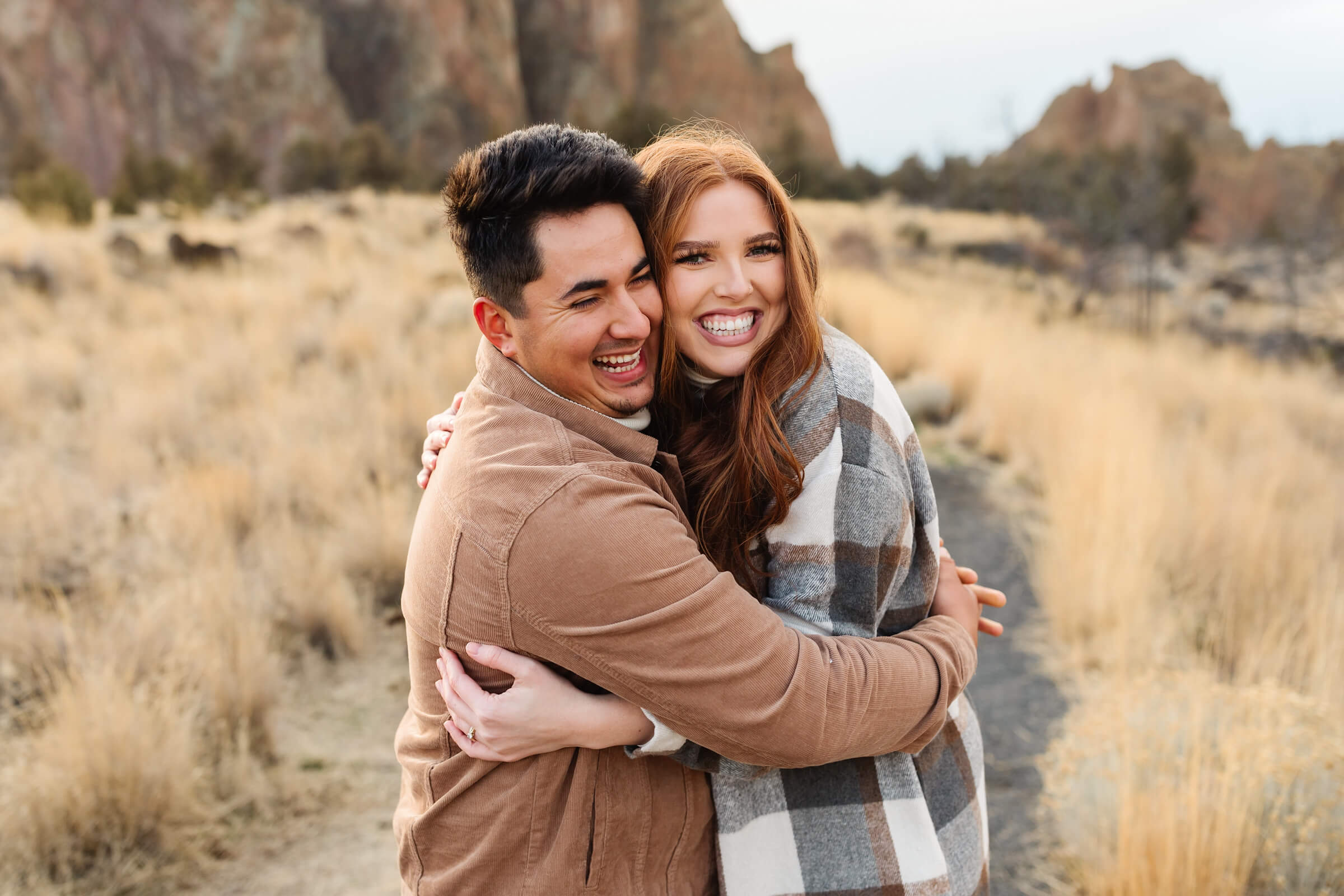 dark haired male in leather jacket cuddled with woman with red hair on during smith rock family photoshoot