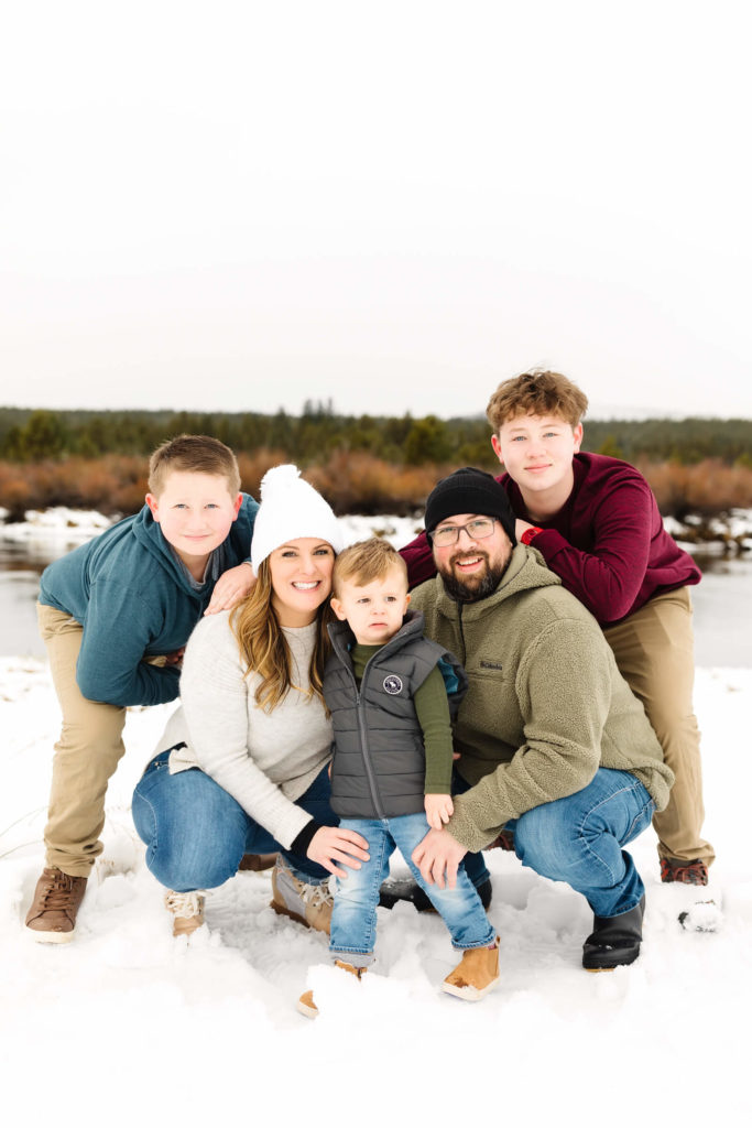 Family of 5 kneeling in snow during family photoshoot in Sunriver Oregon