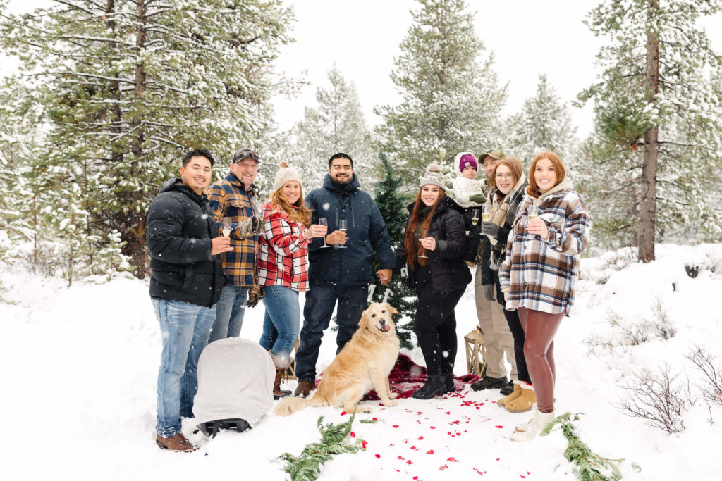 family using champagne to cheers the newly engaged couple in the snow