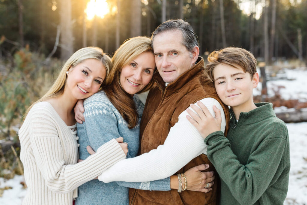 family of four huddles together outside Sunriver vacation rental during family photos