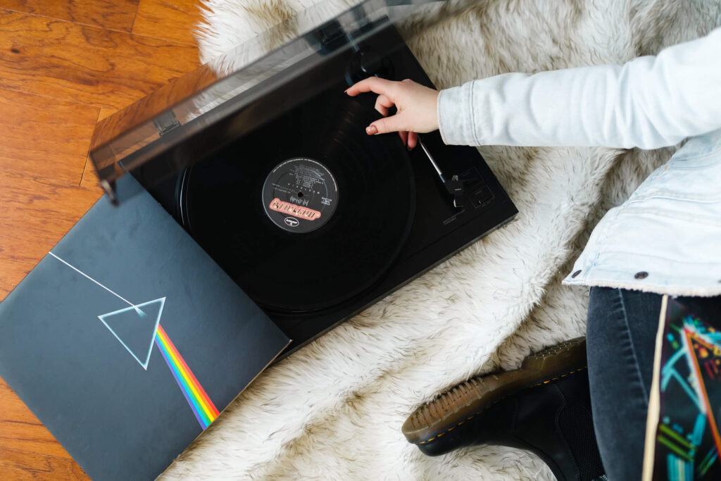 hand putting The Dark Side of the Moon vinyl record on record player during senior photoshoot