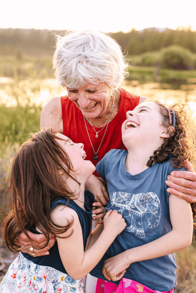 Candid moment of grandmother laughing with granddaughters during an extended family photography session in Sunriver.